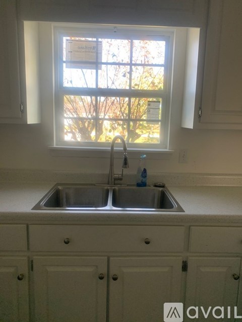 A kitchen with a sink and cabinets under a window.