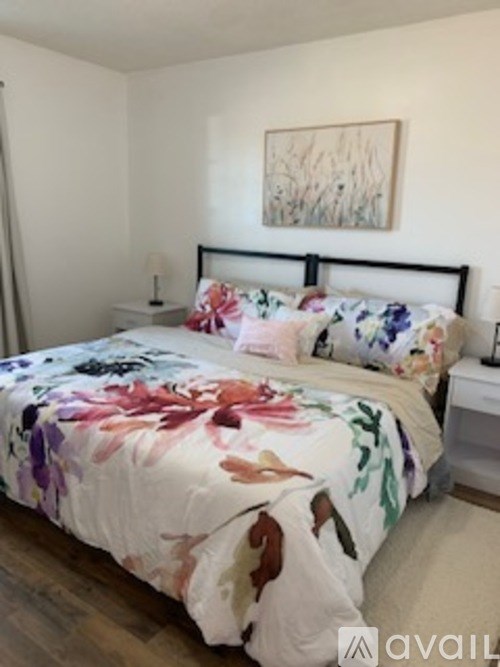 A bedroom with a floral bedspread and a painting on the wall.