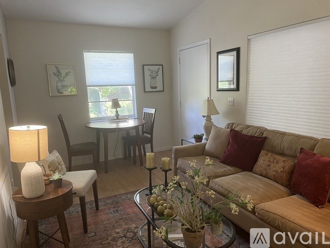 A living room with a couch, chairs, and a table with a lamp and vase.