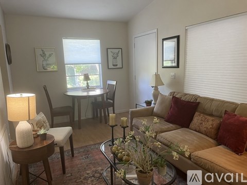 A living room with a couch, chairs, and a table with a lamp and vase.