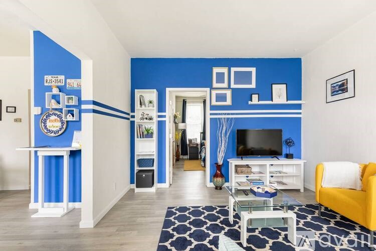 A living room with a blue accent wall and a yellow chair.
