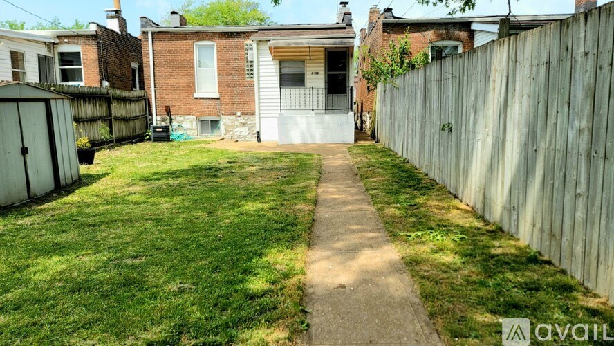 A backyard with a wooden fence and a concrete pathway.