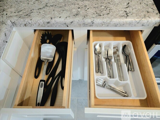 A drawer with utensils and scissors in it.