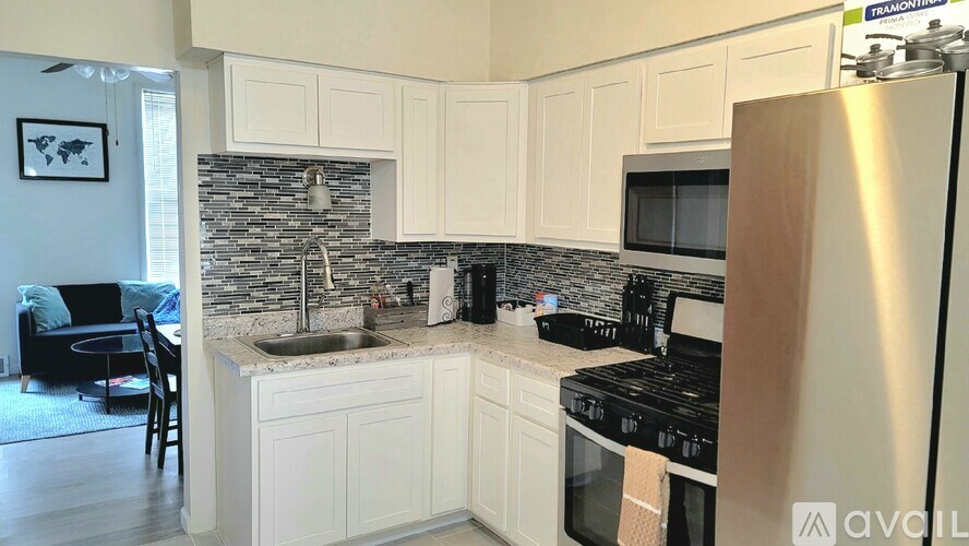 A kitchen with white cabinets and a stainless steel refrigerator.