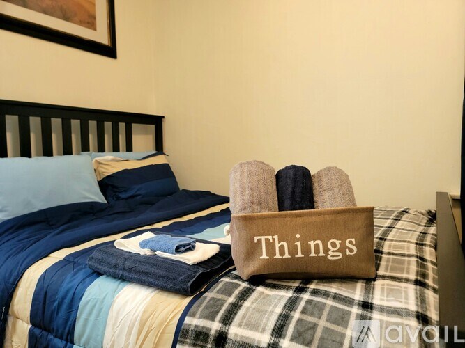 A bed with a plaid comforter and a pillow with a blue cover.