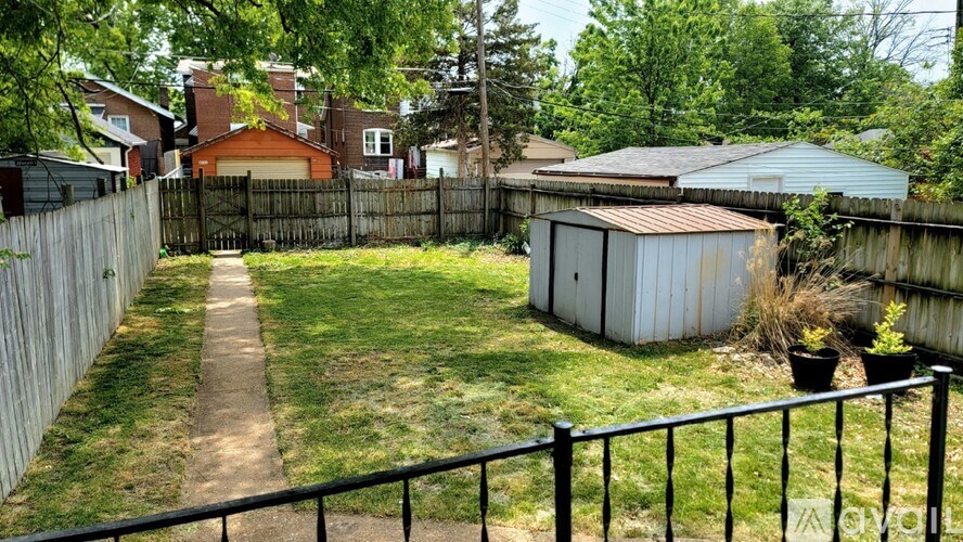 A backyard with a shed and a fence.