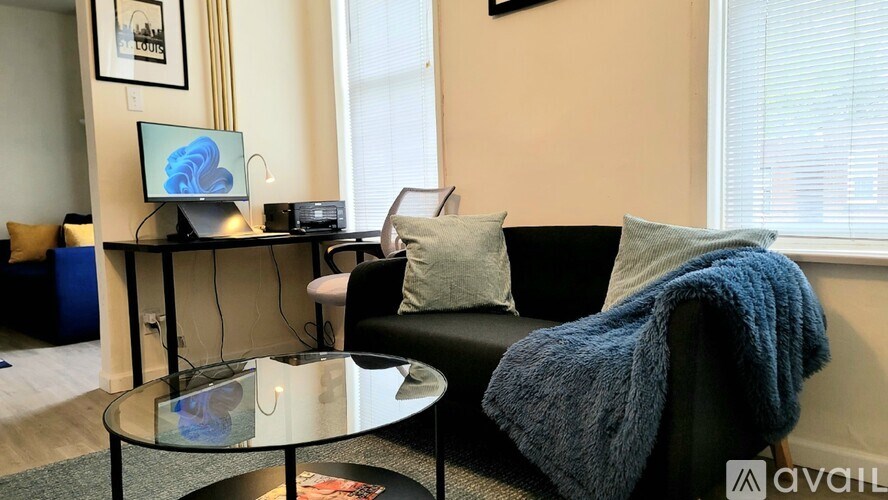 A living room with a couch, a coffee table, and a computer on a desk.