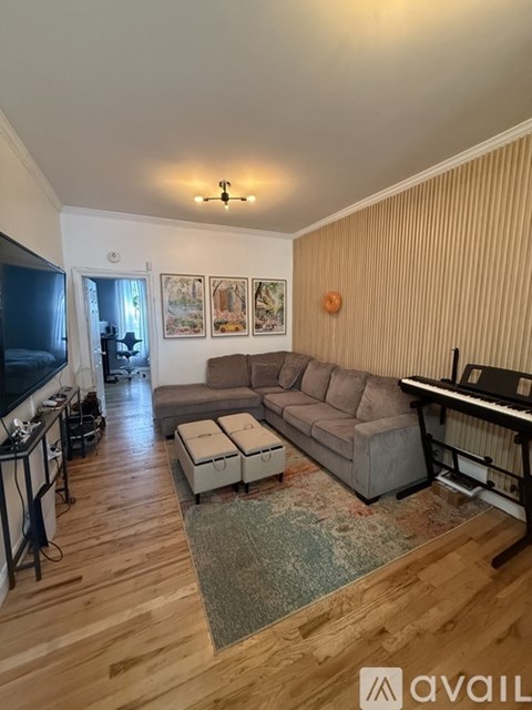 A living room with a grey couch and a piano.