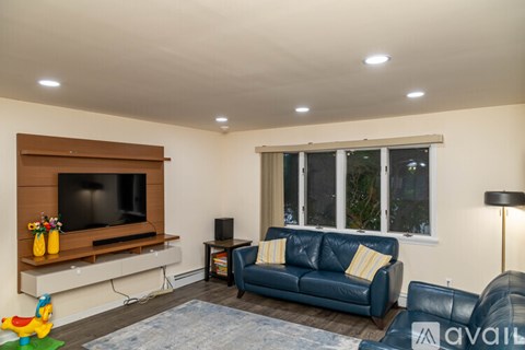 A living room with a blue couch and a television on a wooden stand.