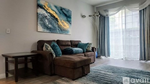 A living room with a brown couch and a painting on the wall.