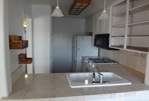 A kitchen with a sink, stove, and refrigerator.