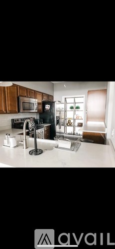 A kitchen with a black refrigerator and a black stove top oven.