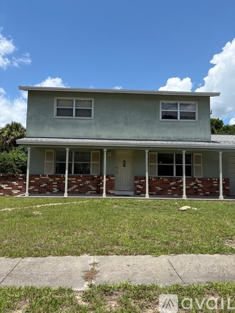 A house with a white door and windows is surrounded by grass.