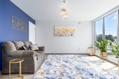 A living room with a grey couch, a gold side table, and a large painting on the wall.