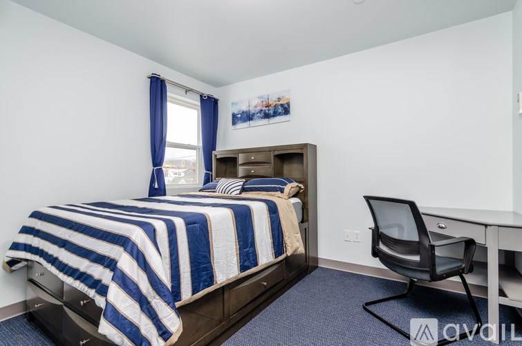 A bedroom with a bed, desk, and chair.