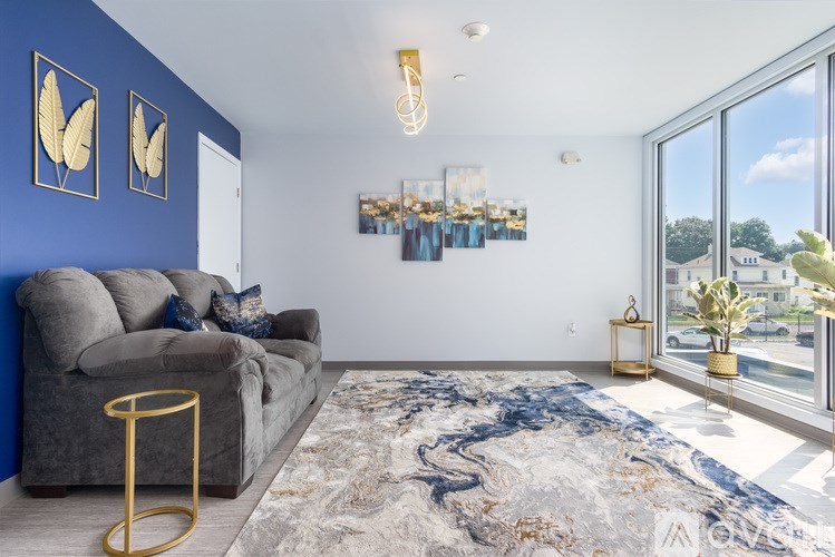 A living room with a grey sofa and a large window.