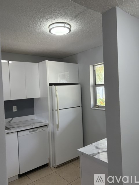 A kitchen with white cabinets and a white fridge.