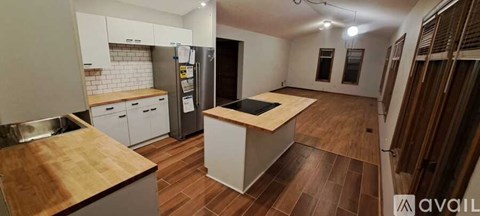 A kitchen with a wooden counter top and white cabinets.