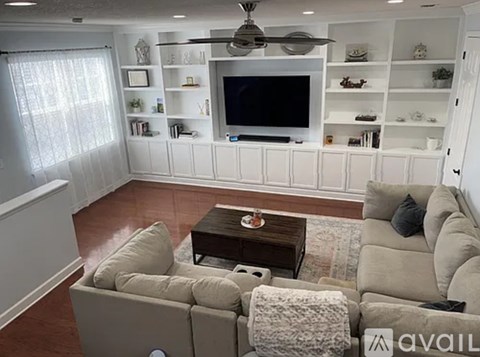 A living room with a couch, coffee table, and a television on a wall.
