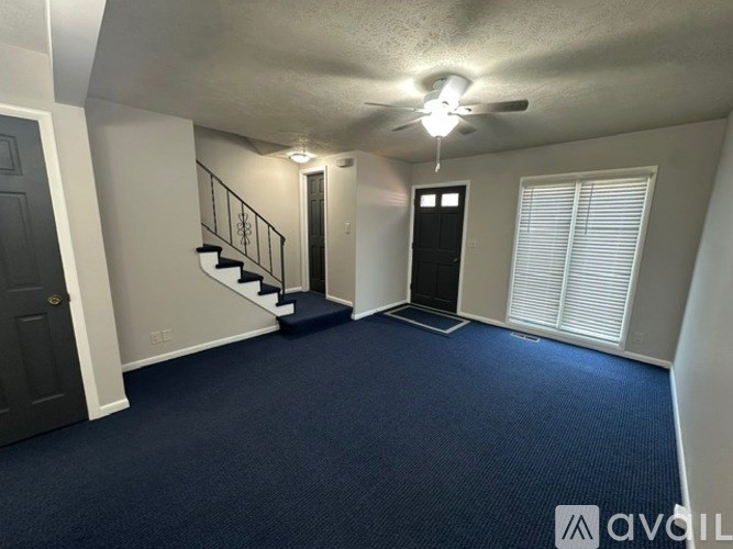 A spacious room with a staircase and a ceiling fan.