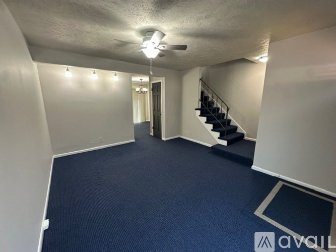 A spacious room with a staircase and lights on the wall.