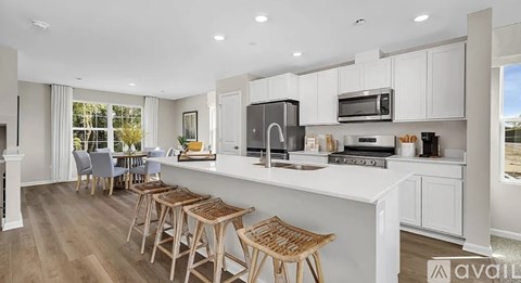 A kitchen with white cabinets and a large island with bar stools.