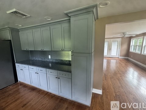 A kitchen with white cabinets and a black countertop.