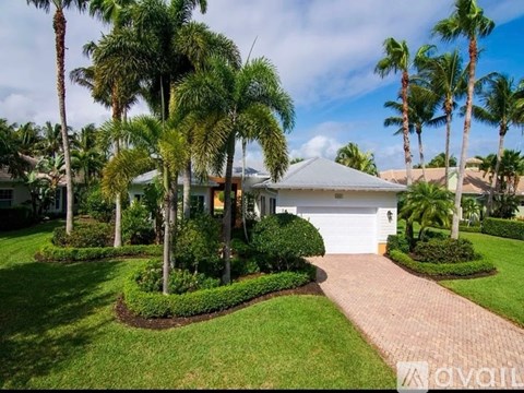 A house with a driveway and palm trees in front.