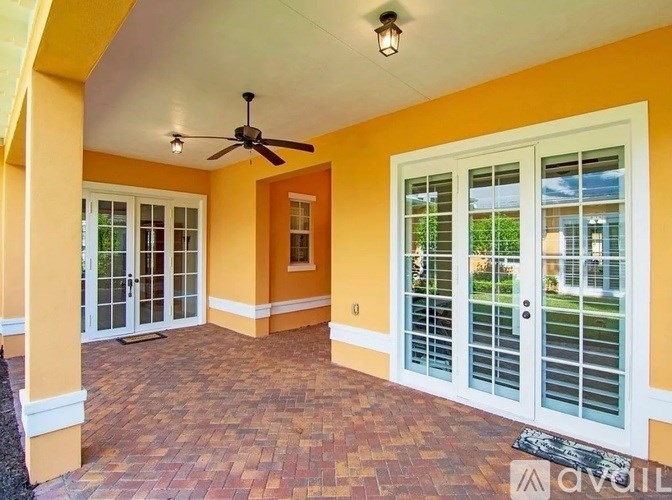 A patio with a ceiling fan and sliding glass doors.