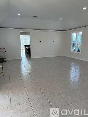 A spacious room with white walls and tile flooring.