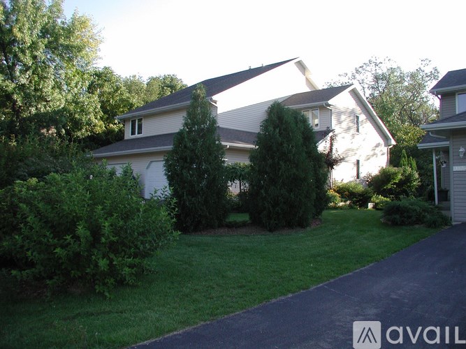 A house with a driveway and greenery in front.