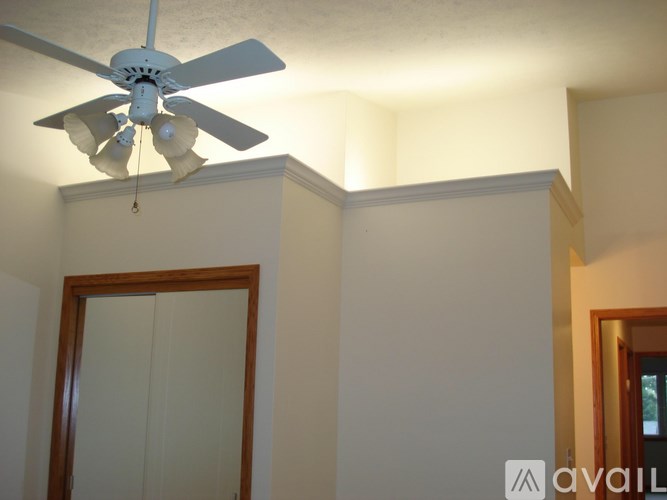 A white ceiling fan hangs from the ceiling in a room with white walls.
