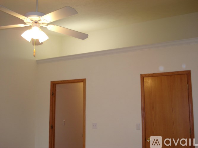 A room with a ceiling fan and two doors.
