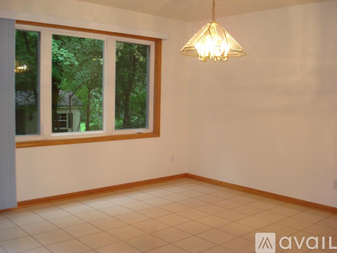A room with a large window and a chandelier hanging from the ceiling.