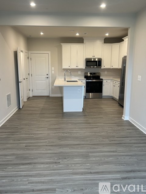 A kitchen with white cabinets and a wooden floor.
