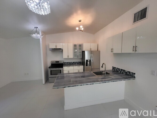 A modern kitchen with a large island and a chandelier.
