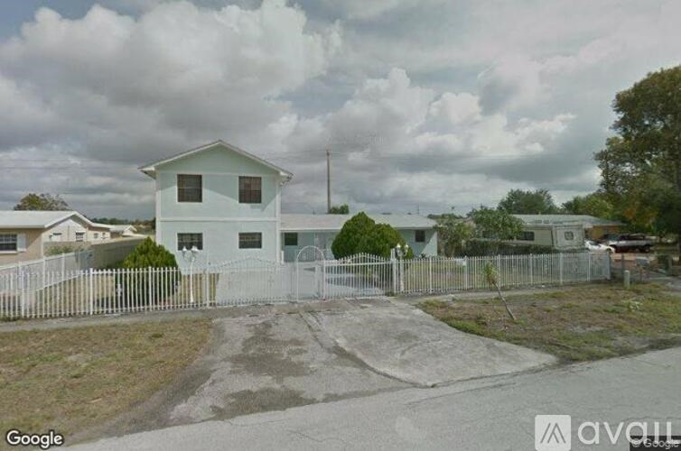 A white house with a grey fence in front of it.