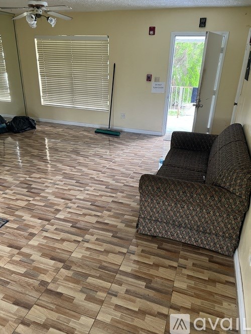 A room with a brown patterned couch and wooden floor.