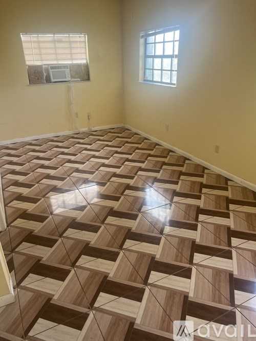A room with a wooden floor and two windows.