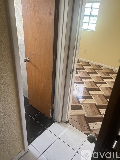 A hallway with a wooden door and a tiled floor.