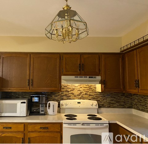 A kitchen with wooden cabinets and a white stove top oven.