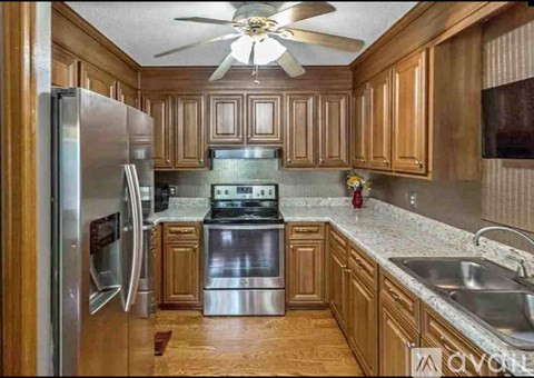 A kitchen with wooden cabinets and a stainless steel refrigerator.