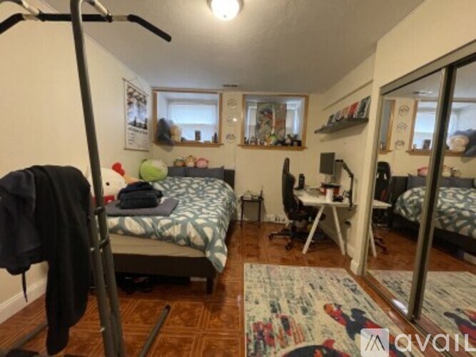 A bedroom with a bed, desk, chair, and mirrors.