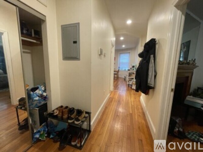 A hallway with a shoe rack and a coat hanging on the wall.
