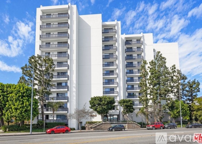 A tennis court is located in front of a tall apartment building.