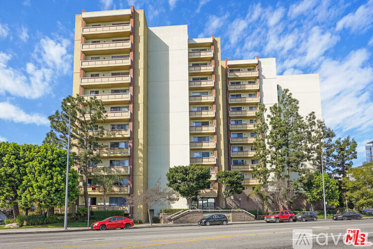 A tall apartment building with a parking lot in front.