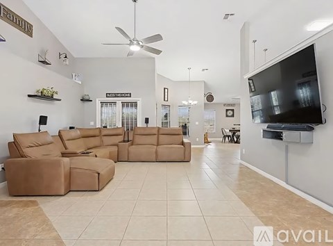 A living room with a large sectional sofa and a flat screen TV mounted on the wall.