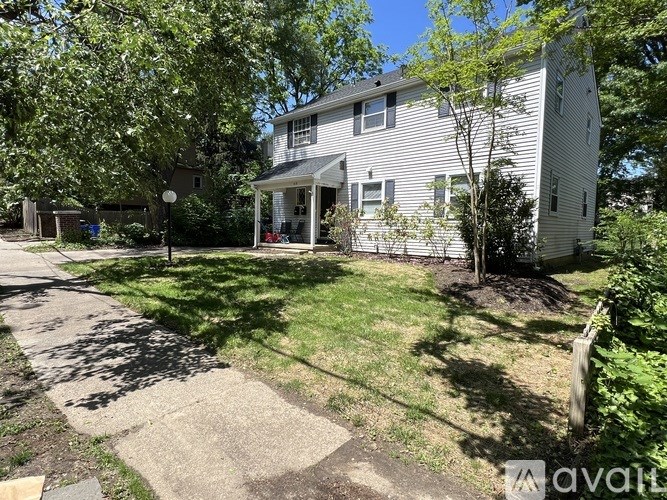 A house with a well-maintained lawn and trees in front.