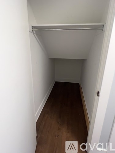 A small, empty room with a wooden floor and white walls.