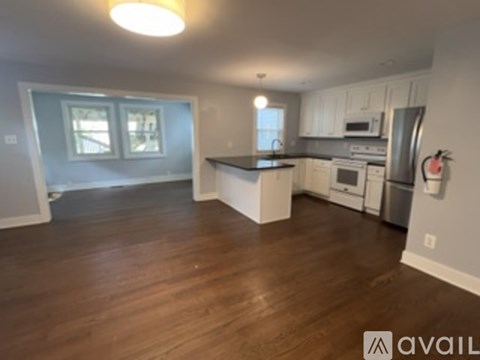 A kitchen with white cabinets and a wooden floor.